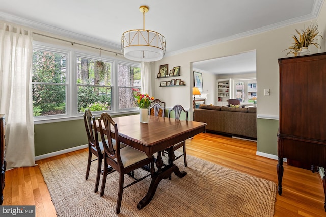 dining room featuring crown molding, baseboards, and light wood-type flooring