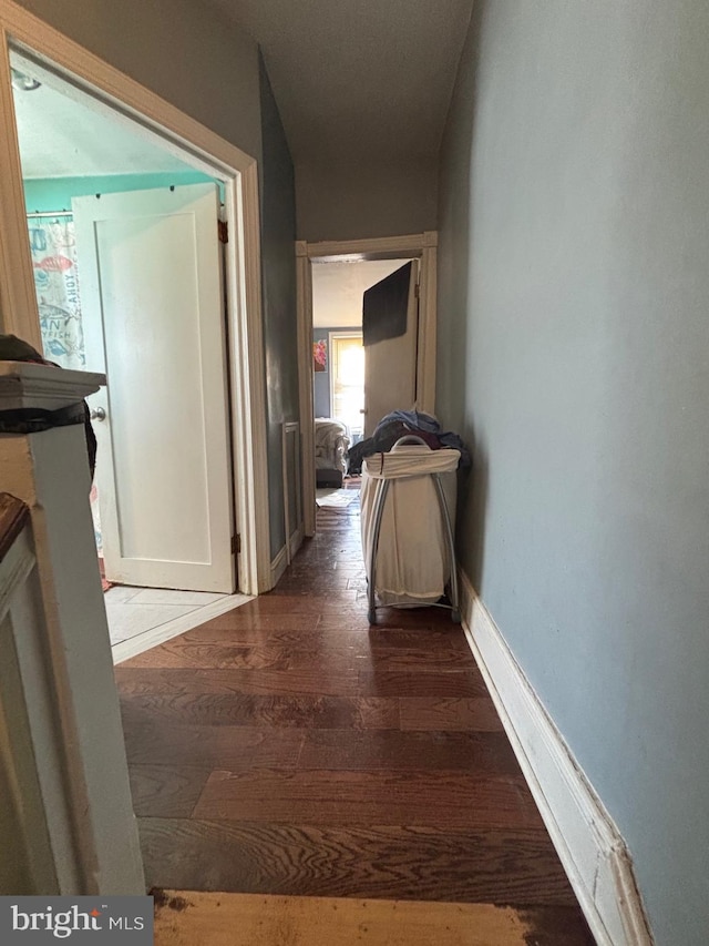 hallway with baseboards and dark wood-style flooring