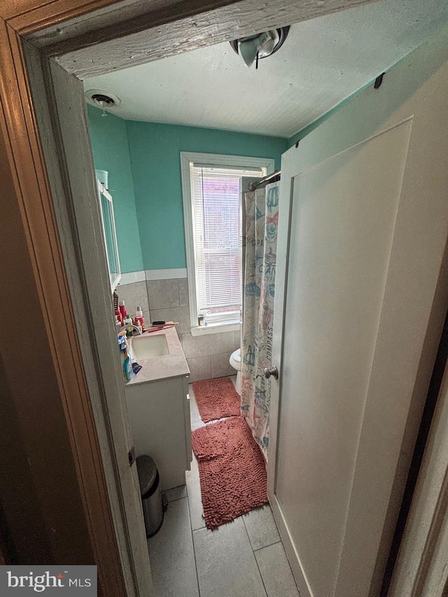 bathroom featuring tile walls, visible vents, toilet, vanity, and tile patterned floors