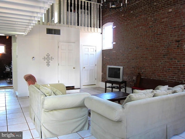 living area featuring light tile patterned flooring, visible vents, and a high ceiling