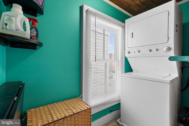 washroom featuring baseboards, laundry area, and stacked washing maching and dryer