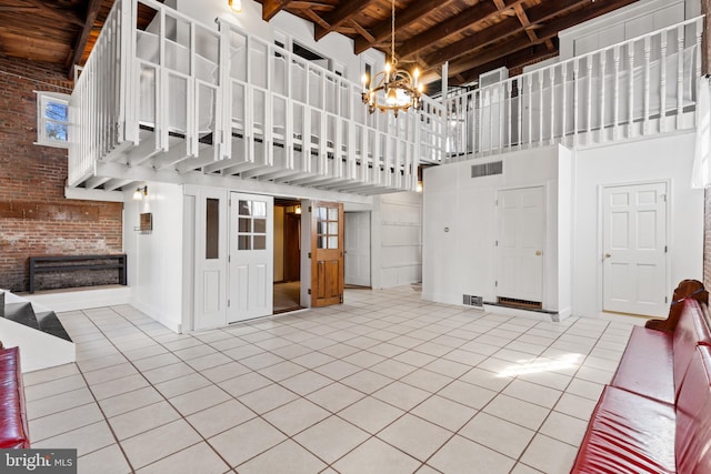 unfurnished living room with beam ceiling, a notable chandelier, wooden ceiling, tile patterned flooring, and a towering ceiling