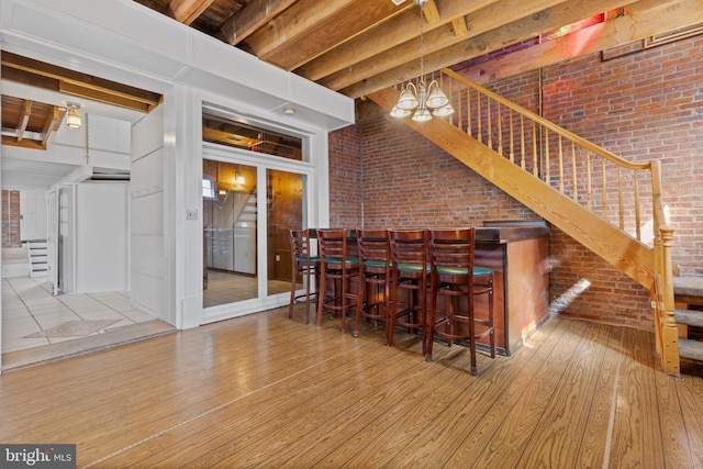 bar with wood finished floors, brick wall, stairs, and a dry bar