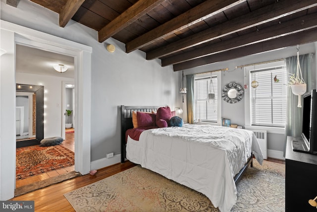 bedroom featuring beam ceiling, wood finished floors, radiator, baseboards, and wood ceiling