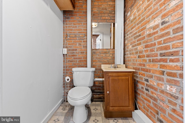 half bath featuring toilet, brick wall, and vanity