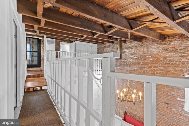 corridor featuring beamed ceiling and brick wall