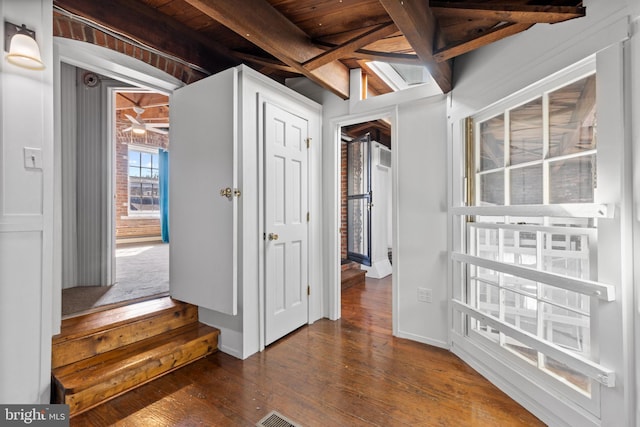 foyer entrance featuring beamed ceiling, dark wood-type flooring, and baseboards