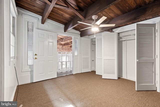 unfurnished bedroom with beamed ceiling, carpet floors, two closets, and wooden ceiling