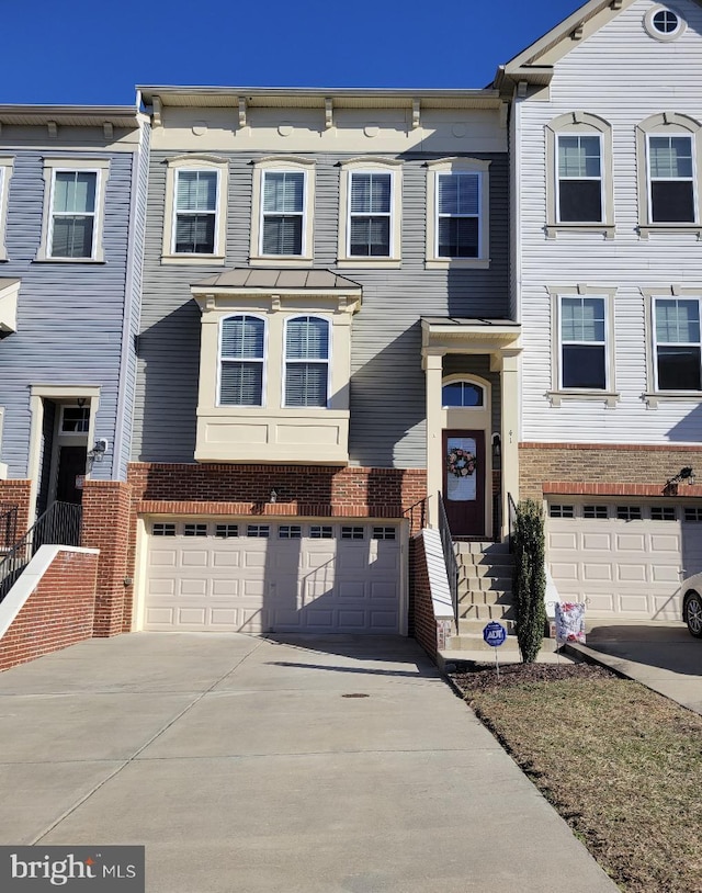 multi unit property featuring an attached garage, concrete driveway, and brick siding