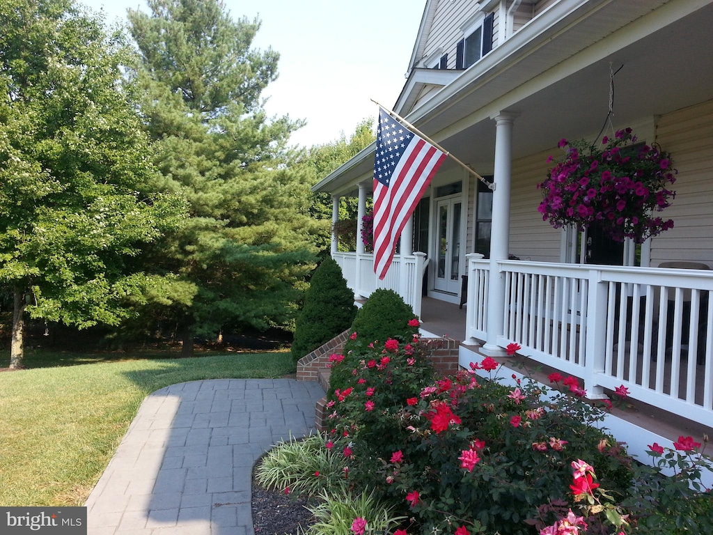 view of property exterior featuring a porch, french doors, and a yard