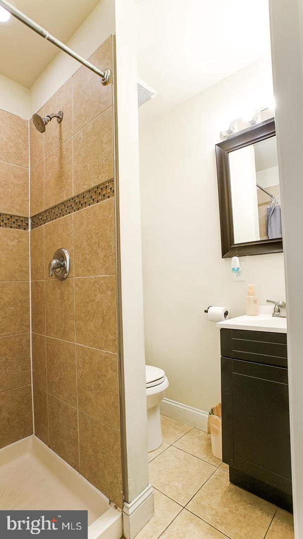 bathroom featuring tile patterned flooring, toilet, vanity, and a shower stall