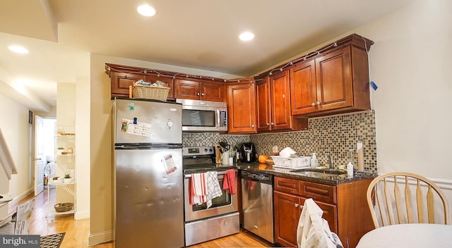 kitchen featuring tasteful backsplash, stainless steel appliances, a sink, and light wood-style flooring