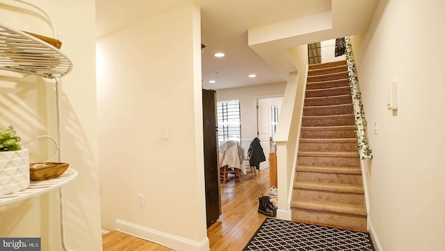 staircase with recessed lighting, baseboards, and wood finished floors