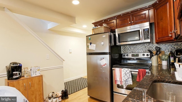 kitchen with dark stone counters, wood finished floors, stainless steel appliances, backsplash, and recessed lighting