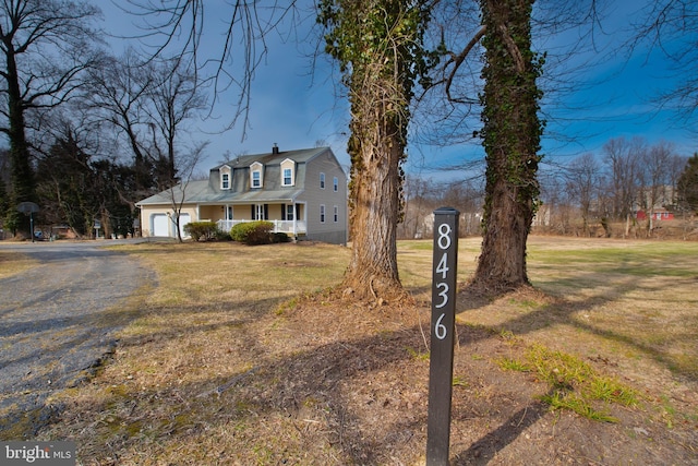 view of front of property featuring a garage, driveway, a porch, and a front yard