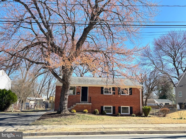 view of front of house with brick siding, a front lawn, and fence