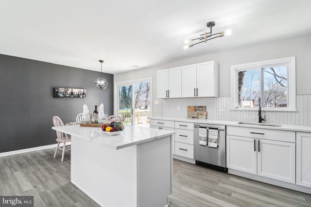 kitchen featuring a chandelier, stainless steel dishwasher, light wood-style floors, white cabinets, and a sink