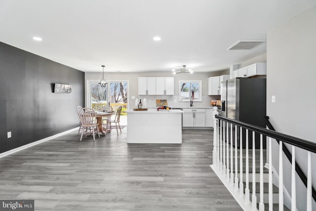 kitchen with visible vents, decorative backsplash, light countertops, white cabinetry, and stainless steel fridge