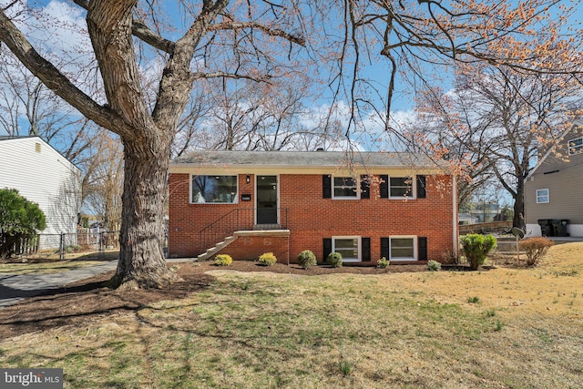 view of front of house with brick siding, a front yard, and fence