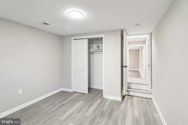 unfurnished bedroom with visible vents, light wood-style floors, baseboards, and a closet