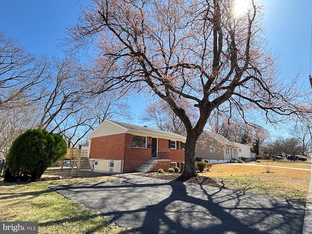 view of front of property featuring a gate, brick siding, a front lawn, and fence