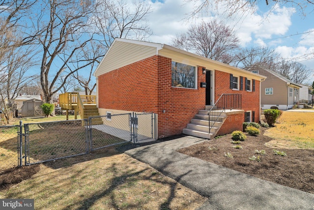 view of front facade with brick siding, aphalt driveway, an outdoor structure, a storage unit, and a gate