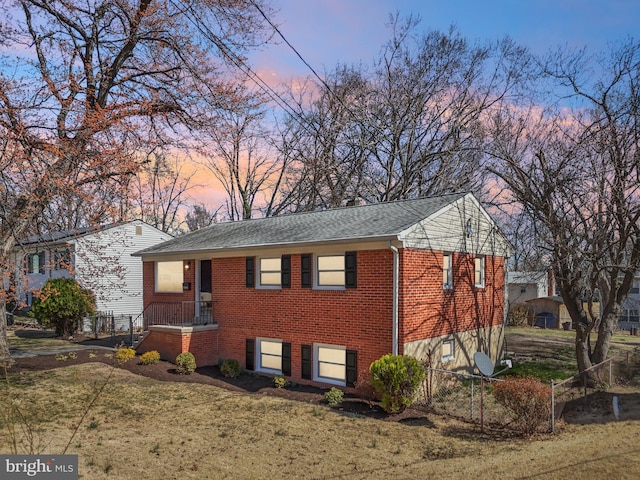 view of front of property featuring a shingled roof, fence, brick siding, and a lawn