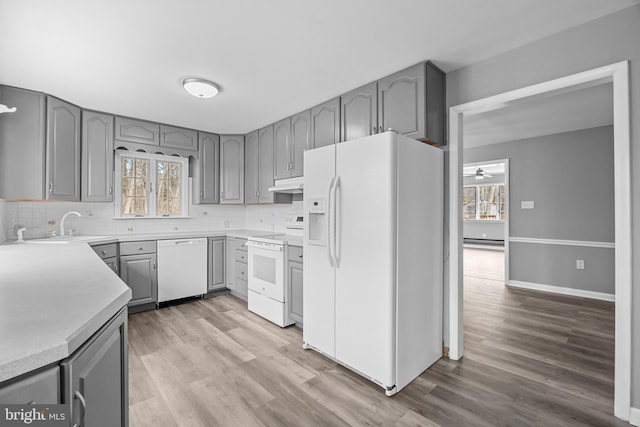 kitchen featuring white appliances, gray cabinets, light wood-style flooring, and under cabinet range hood