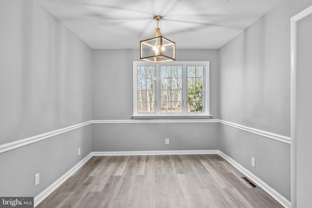 unfurnished dining area with baseboards, visible vents, and wood finished floors