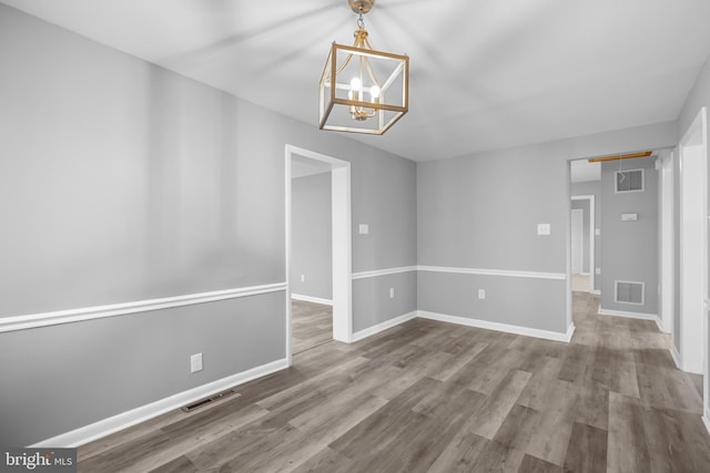 unfurnished dining area featuring baseboards, visible vents, and wood finished floors