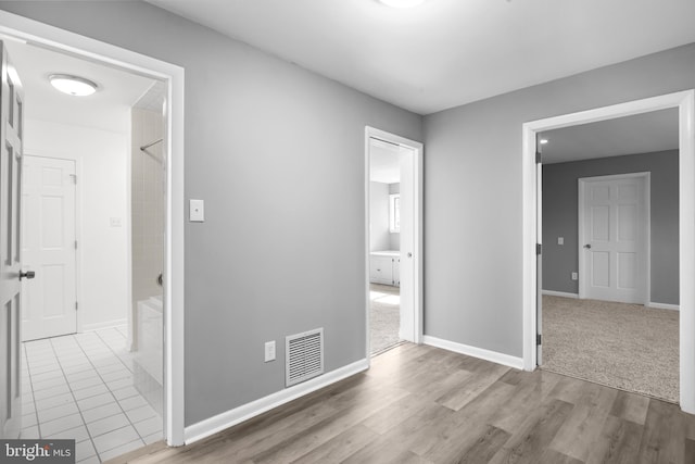 corridor featuring visible vents, baseboards, and wood finished floors