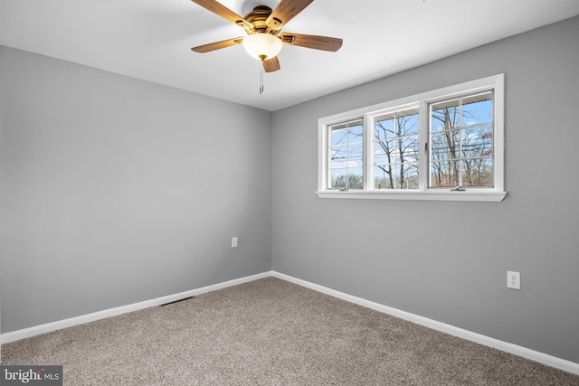 carpeted empty room featuring ceiling fan and baseboards