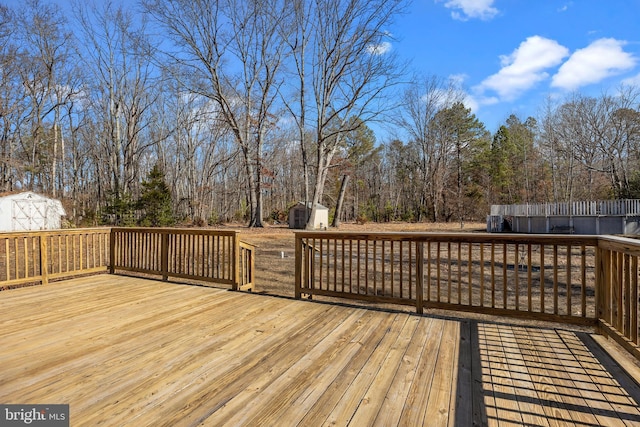 wooden terrace featuring a shed and an outdoor structure