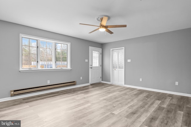 foyer entrance with baseboard heating, wood finished floors, a ceiling fan, and baseboards