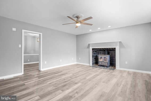 unfurnished living room with visible vents, wood finished floors, a wood stove, and baseboards