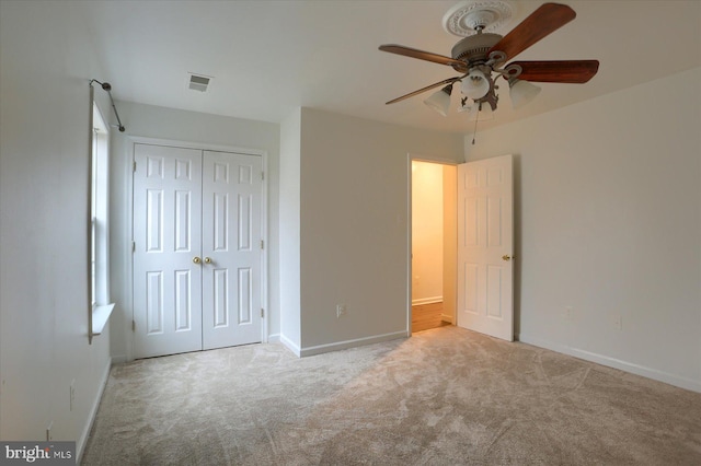 unfurnished bedroom with baseboards, visible vents, a ceiling fan, carpet, and a closet