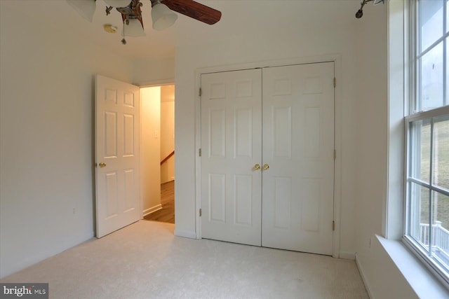 unfurnished bedroom with a ceiling fan, a closet, and light colored carpet