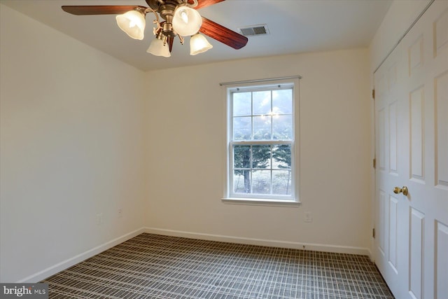 carpeted empty room with a ceiling fan, visible vents, and baseboards