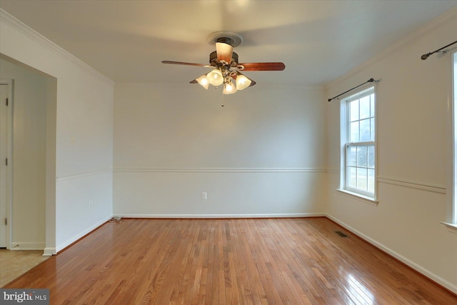 unfurnished room featuring visible vents, baseboards, a ceiling fan, wood-type flooring, and crown molding