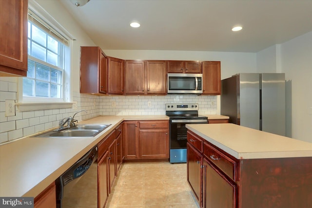 kitchen with light countertops, appliances with stainless steel finishes, a sink, and decorative backsplash