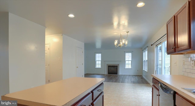 kitchen with light countertops, a fireplace with flush hearth, brown cabinetry, a kitchen island, and dishwasher