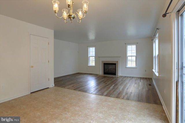 unfurnished living room with a chandelier, a fireplace, baseboards, and tile patterned floors