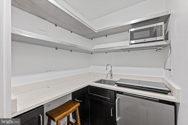 kitchen with dark cabinets, stainless steel microwave, and a sink