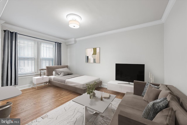 bedroom featuring baseboards, ornamental molding, and wood finished floors