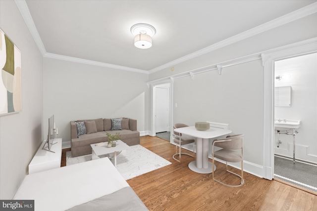 living area featuring ornamental molding, wood finished floors, and baseboards