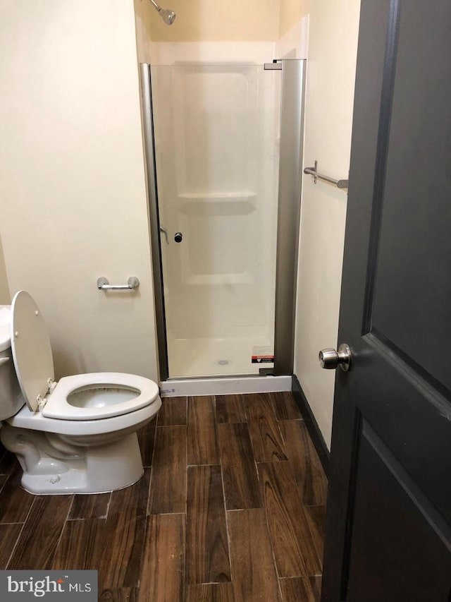 full bathroom with toilet, a shower stall, and wood tiled floor