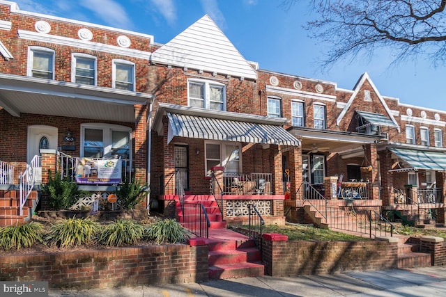 townhome / multi-family property featuring a porch, brick siding, and stairway