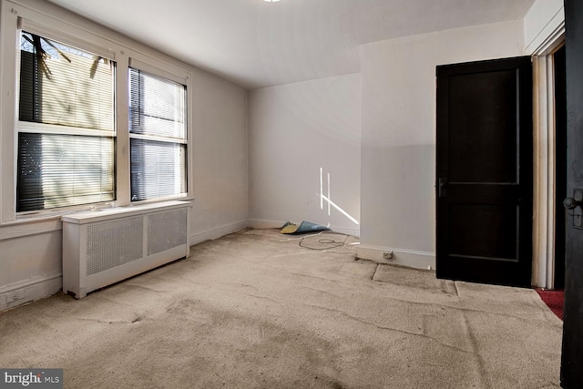 spare room with carpet floors, radiator heating unit, and baseboards