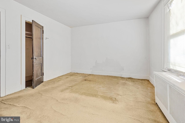 empty room with carpet floors and radiator heating unit