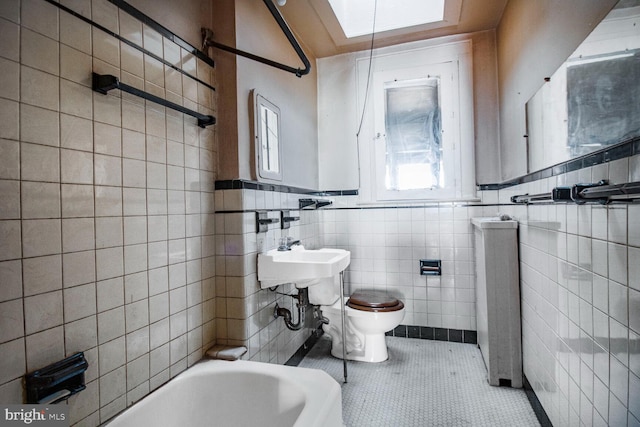 full bathroom with a wainscoted wall, tile walls, toilet, and tile patterned floors